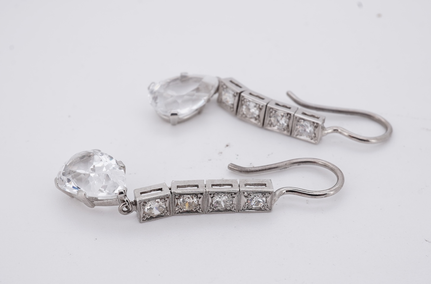 A pair of white metal and four stone diamond set earrings, each with a cubic zirconia pear shaped drop, overall 42mm.